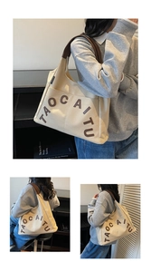 Detail of canvas tote bag with brown leather handles and TAOCAITU letter patch