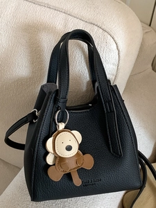 Borsa a secchiello vintage in pelle nera con ciondolo a forma di animale su divano beige