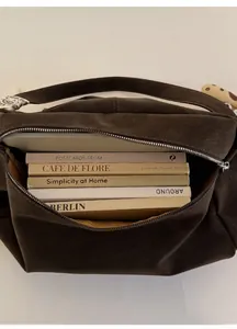 Detail view of large brown suede tote bag showing spacious interior with books and silver zipper