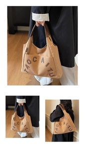 Close-up of canvas tote bag with leather handles and contrast TAOCAITU letter print