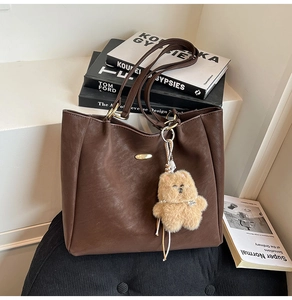 Brown faux leather tote bag with gold logo plate and a cute plush bear charm detail