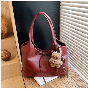 Detail of burgundy tote bag with bow decoration and cute brown plush puppy pendant
