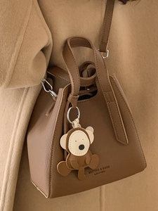 Borsa a secchiello vintage in pelle caramello con ciondolo a orso e tracolla elegante