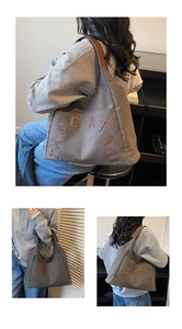 Detail view of large canvas tote bag with leather letter patches and wide shoulder strap