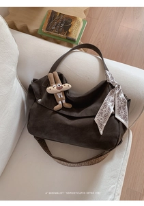 Detail of a brown tote bag with woven strap, floral silk scarf, and cute rabbit charm