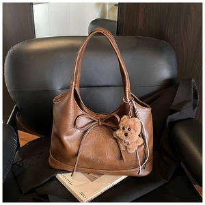 Detail of vintage brown tote bag with leather bow decoration and plush dog pendant