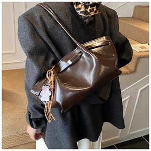 Detailed view of brown glossy tote bag with stylish leopard print bear charm accessory