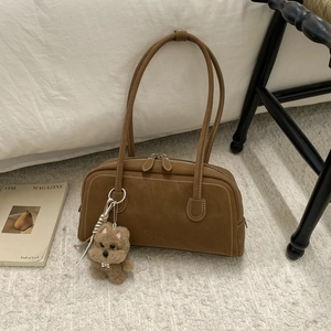 Detail shot of brown vintage bowling bag with contrast stitching and plush puppy charm