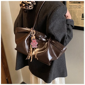 Detail view of dark brown glossy leather tote bag with leopard bear and tassel charms