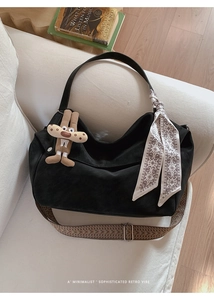 Detail of black vintage hobo bag with woven strap and silk scarf on a white sofa