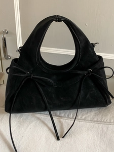 Sac à main élégant en cuir noir avec poignées rondes et nœuds décoratifs sur les côtés