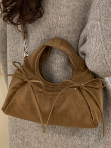 Sac à main marron en suédine avec nœuds décoratifs et bandoulière sur pull gris