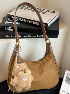 Brown suede hobo shoulder bag for women with plush puppy charm on artistic book stack
