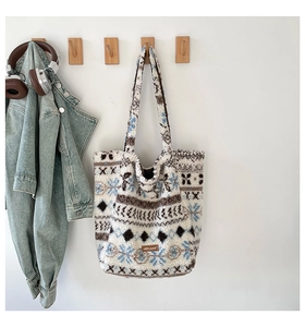 Détail d'un sac cabas en peluche avec motif flocon suspendu dans un décor décontracté