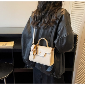 Détail d'un sac bandoulière crème chic avec des perles en bois et une bandoulière