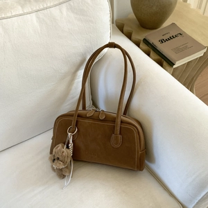 Close-up of retro brown shoulder bag with white stitching and a cute plush dog charm