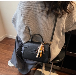 Détail d'un sac carré noir rétro en similicuir texturé avec une breloque en perles colorées
