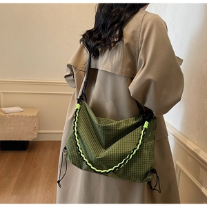 Detail of green checkered crossbody bag with woven rope chain and drawstring feature