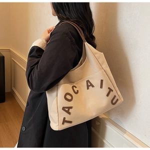Detail of canvas tote bag with brown TAOCAITU letter patch and spacious design