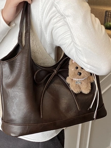 Deep brown leather tote bag with bow detail and plush puppy charm for women