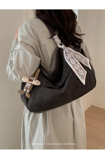 Detailed side view of charcoal grey hobo bag with paisley scarf and puppy charm