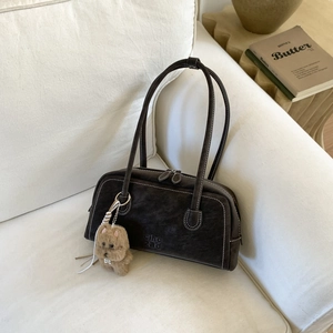 Detail of dark brown Boston bag with contrast stitching and plush bear charm