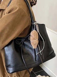 Large black leather tote bag with plush charm, minimalist aesthetic for women