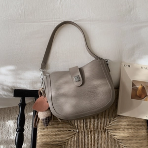 Detail of taupe lychee leather bucket bag with silver buckle and heart-shaped pendant charm