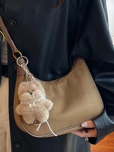 Brown suede shoulder bag with plush charm, perfect for stylish winter 2025 fashion
