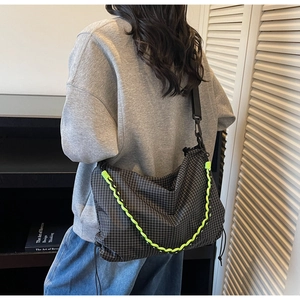 Detail of checkered crossbody bag featuring neon green rope and adjustable black strap