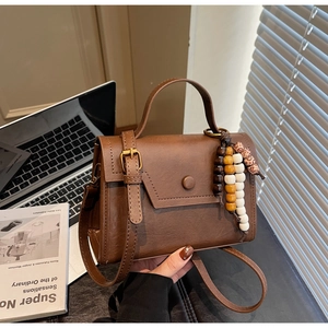 Détail d'un petit sac bandoulière vintage marron avec perles et rabat asymétrique