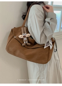 Detail of retro brown tote bag with decorative scarf and cute doll charm accessory