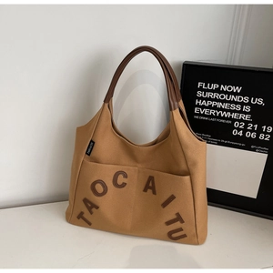 Detail of canvas tote bag with leather straps and front pocket in caramel brown