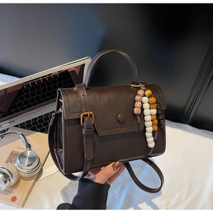 Détail du sac à main vintage marron foncé avec texture cuir et breloque en perles