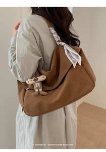 Close-up of brown suede tote bag with decorative silk scarf and quirky charm detail
