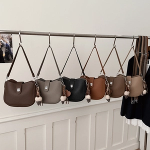 Detailed display of six colorful litchi grain leather saddle bags with fluffy charms