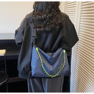 Detail of blue checkered crossbody bag featuring yellow braided handle and large capacity