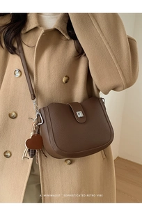 Detail of brown lychee texture crossbody bag with heart pendant and metal clasp