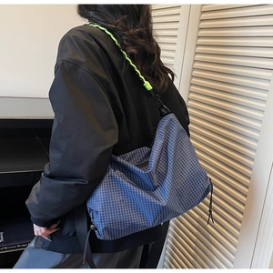Detail of blue checkered tote bag with neon green woven strap and drawstring features