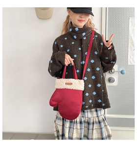 Détail d'un sac rouge en forme de gant avec bordure en peluche blanche et bandoulière fine
