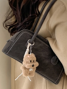 Plush puppy bag charm with VIP DOG tag on a stylish brown suede bowling shoulder bag