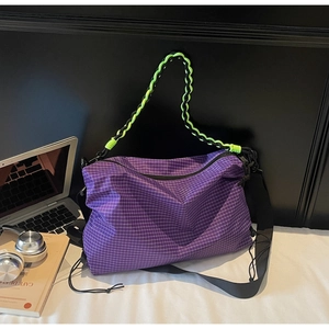 Detail view of purple plaid tote bag featuring neon green rope handle on an office desk