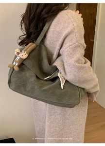 Detail of dark green matte shoulder bag with cute brown plush bunny charm and white side label