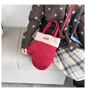 Détail du sac bandoulière rouge en forme de gant avec bordure en peluche et logo en cuir
