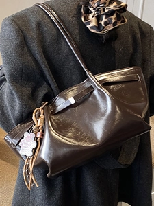 Deep brown glossy leather tote bag with a bear charm pendant for stylish commuting