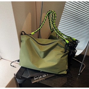 Detail of army green checkered tote bag with woven handles and wide nylon shoulder strap
