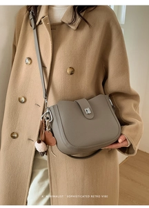 Detail of lychee pattern leather bucket bag with silver buckle and heart charm on a coat
