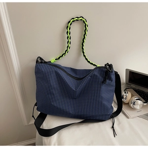 Detail of blue grid crossbody bag featuring dual-tone woven handles and drawstring sides