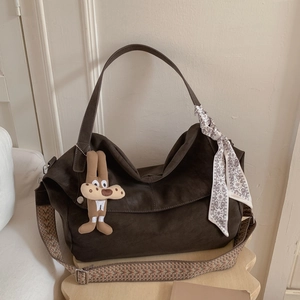 Detail of dark brown suede tote bag with woven shoulder strap and rabbit charm accessory