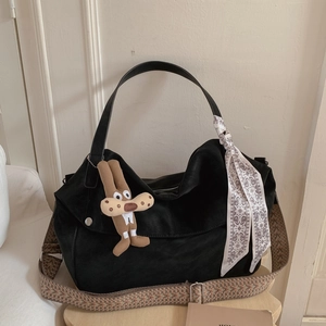 Detail view of black tote bag with ethnic woven strap and decorative scarf accent